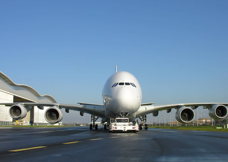 Airbus A380 being towed by tug on taxiway